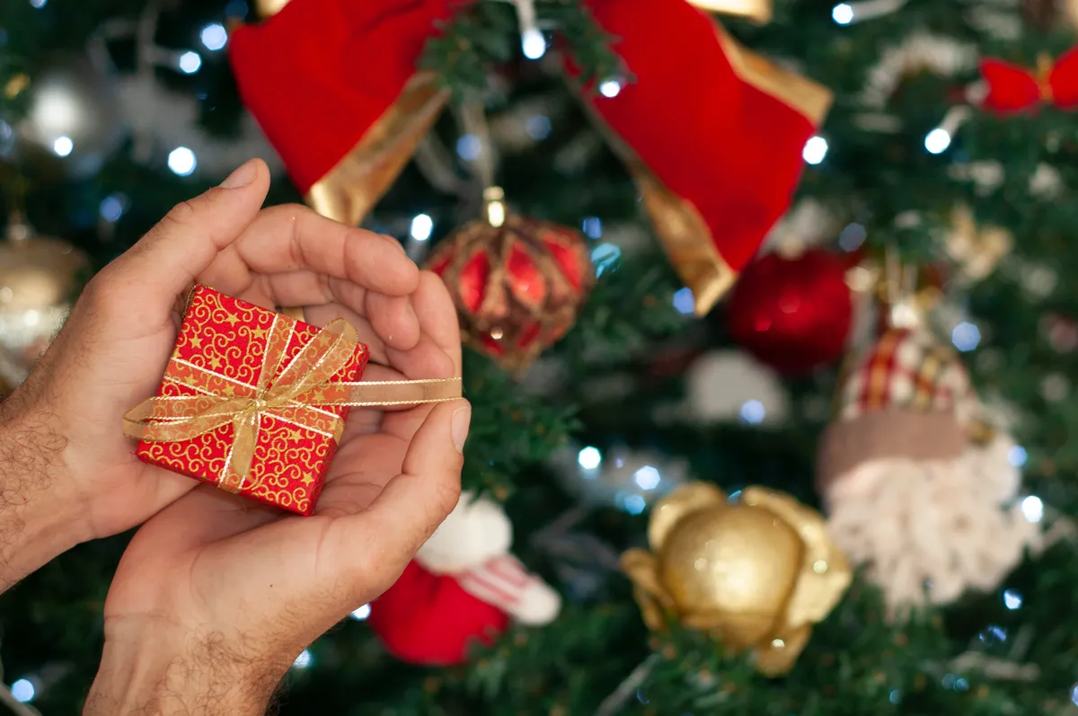 Piros kis ajándékdoboz a karácsonyfa díszei között