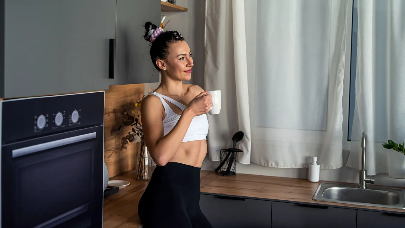 Diétás kávét fogyasztó fiatal nő a konyhában