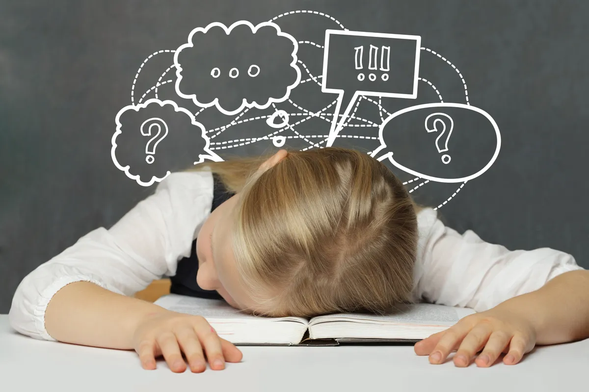 Egy kisfiú egy nyitott könyvön fekszik, nem sikerült túl jól neki a kvíz.