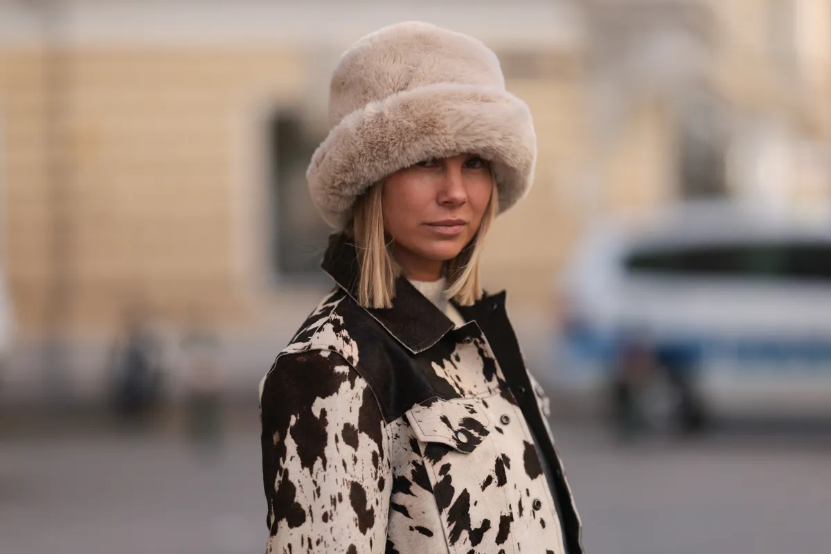 Bolyhos kalapot viselő nő, ami a téli sapkatrend egyik legstílusosabb darabja.