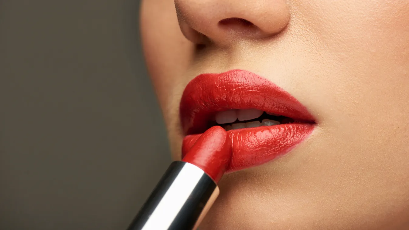 Fiatal nő piros rúzst ken ajkaira.