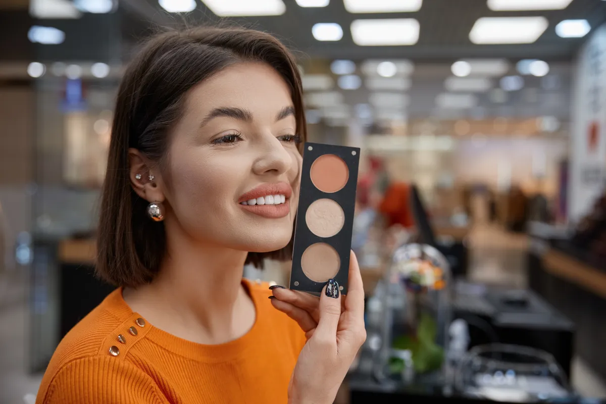 Egy nő épp a bronzosítópalettákat nézi, sminktippjeink alapján választja ki a befutót, amit megvásárol.