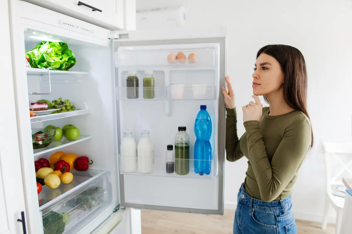 Diétás vacsora alapanyagait a hűtőben kereső nő