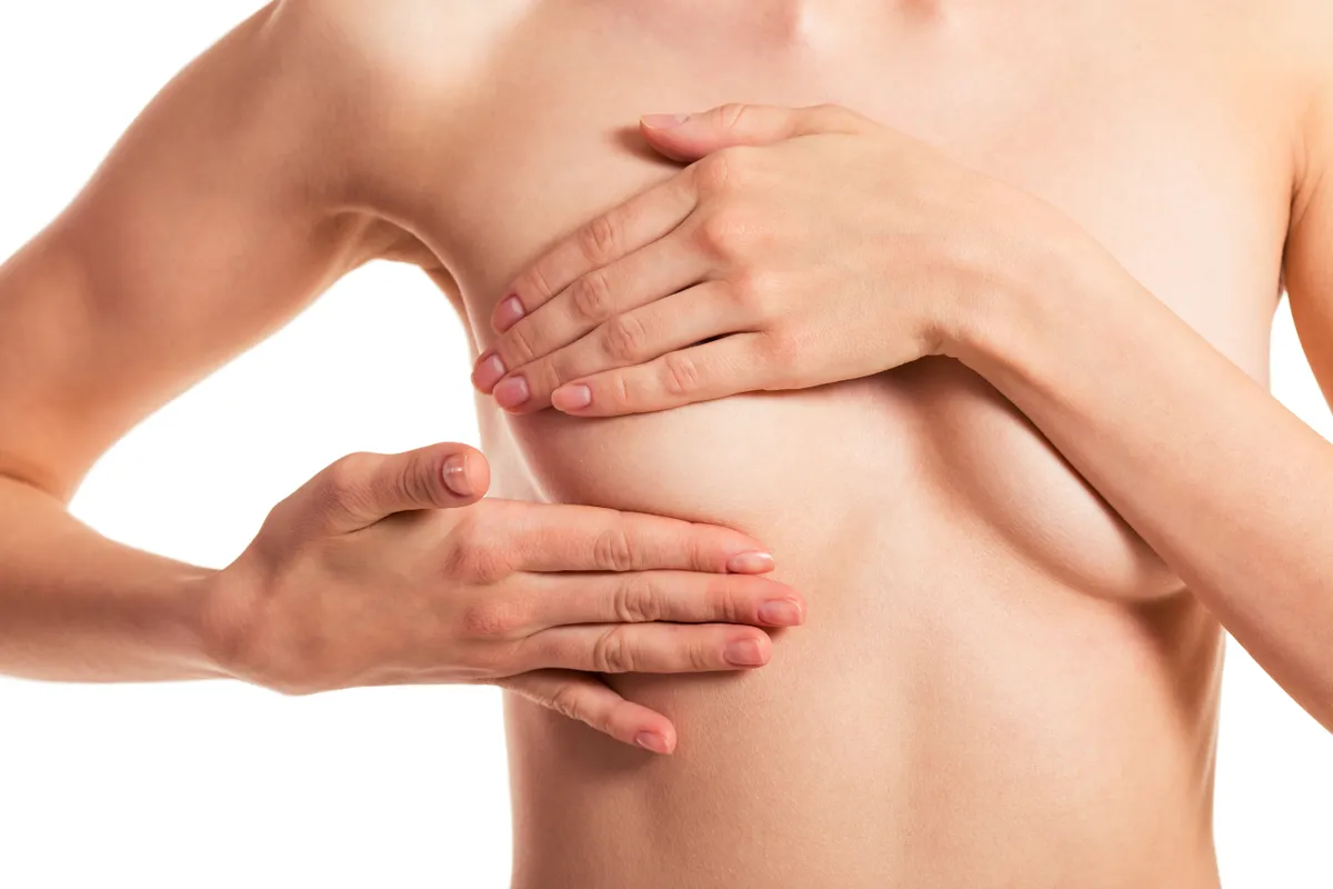 Egy nő épp önvizsgálatot végez, a mellrák tüneteit keresi.