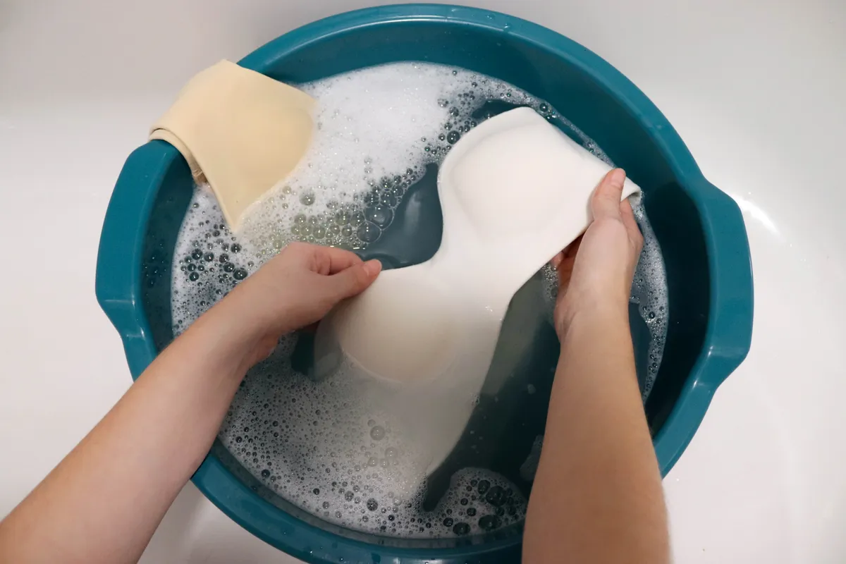 Melltartó mosása kézzel egy lavorban.