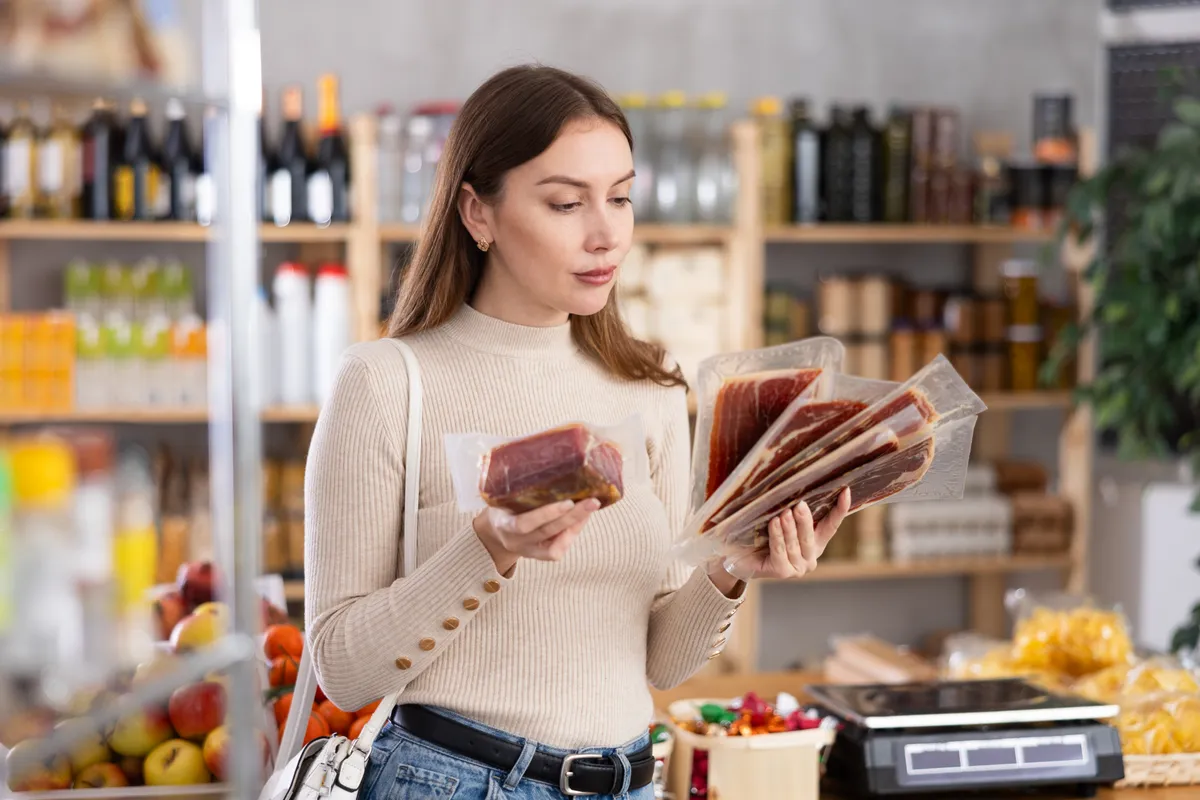 Egy nő épp a termékek összetevőjének listáját nézi, hogy elkerülje, hogy egészségtelen ételeket vegyen.