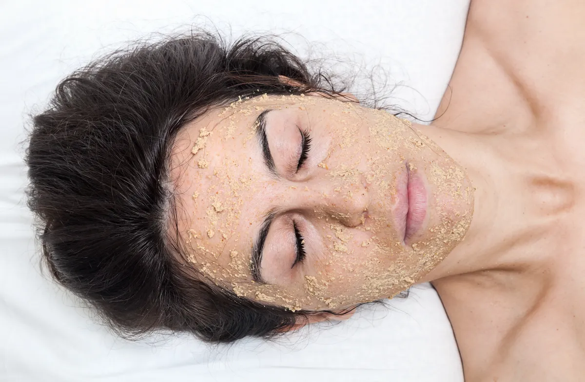 Egy nő filléres házi arcpakolásban fekszik az ágyon.
