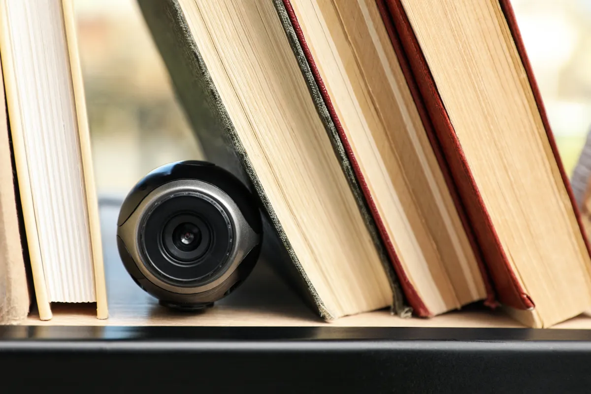 rejtett kamera egy könyves polcon, a könyvek között.