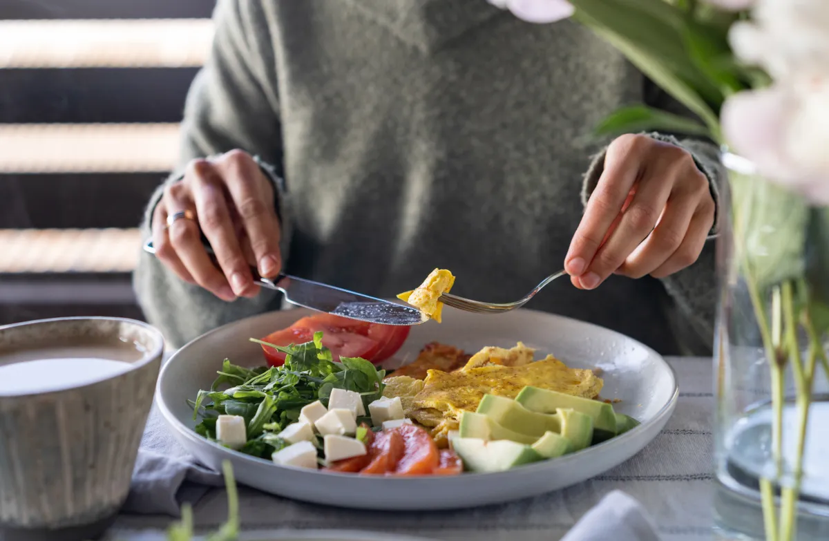 Egészséges diétatipp alapján zöldségeket és tojást evő nő