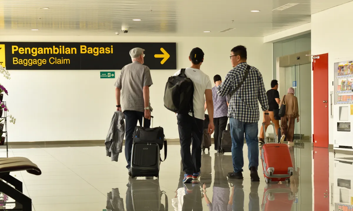 Emberek csoportja egy ázsiai reptéren a kézipoggyászukkal