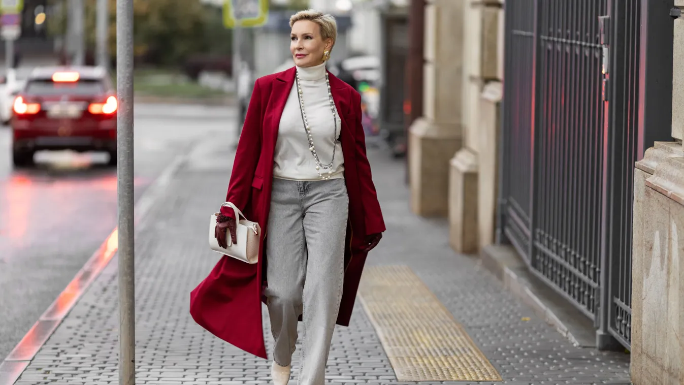 Stílusos középkorú nő bő szárú nadrágban és piros kabátban.