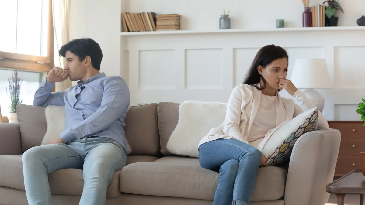 Hűtlenség miatt sértődött fiatal pár a kanapén.