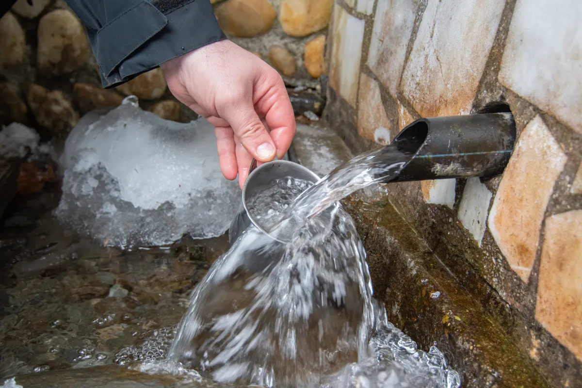 Esővízgyűjtő téliesítése közben lefolyót takarító férfi.