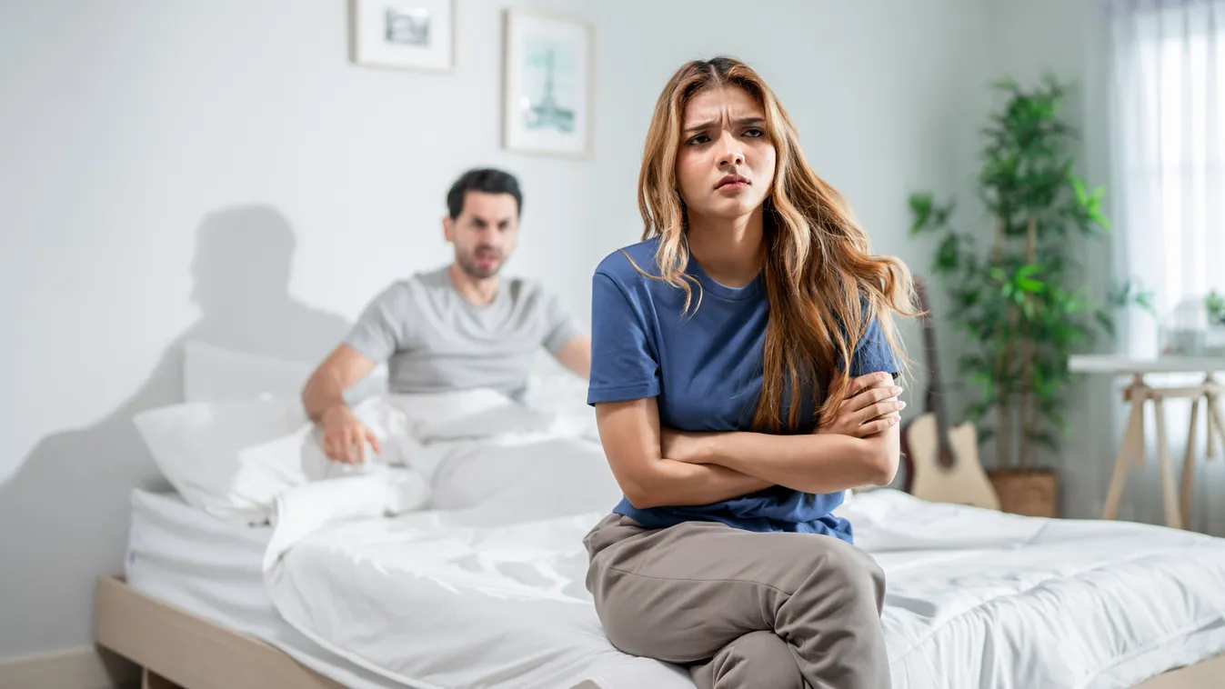 Érzelmi eltávolodás tapasztaló pár tagjai a hálószobai ágyon ülve
