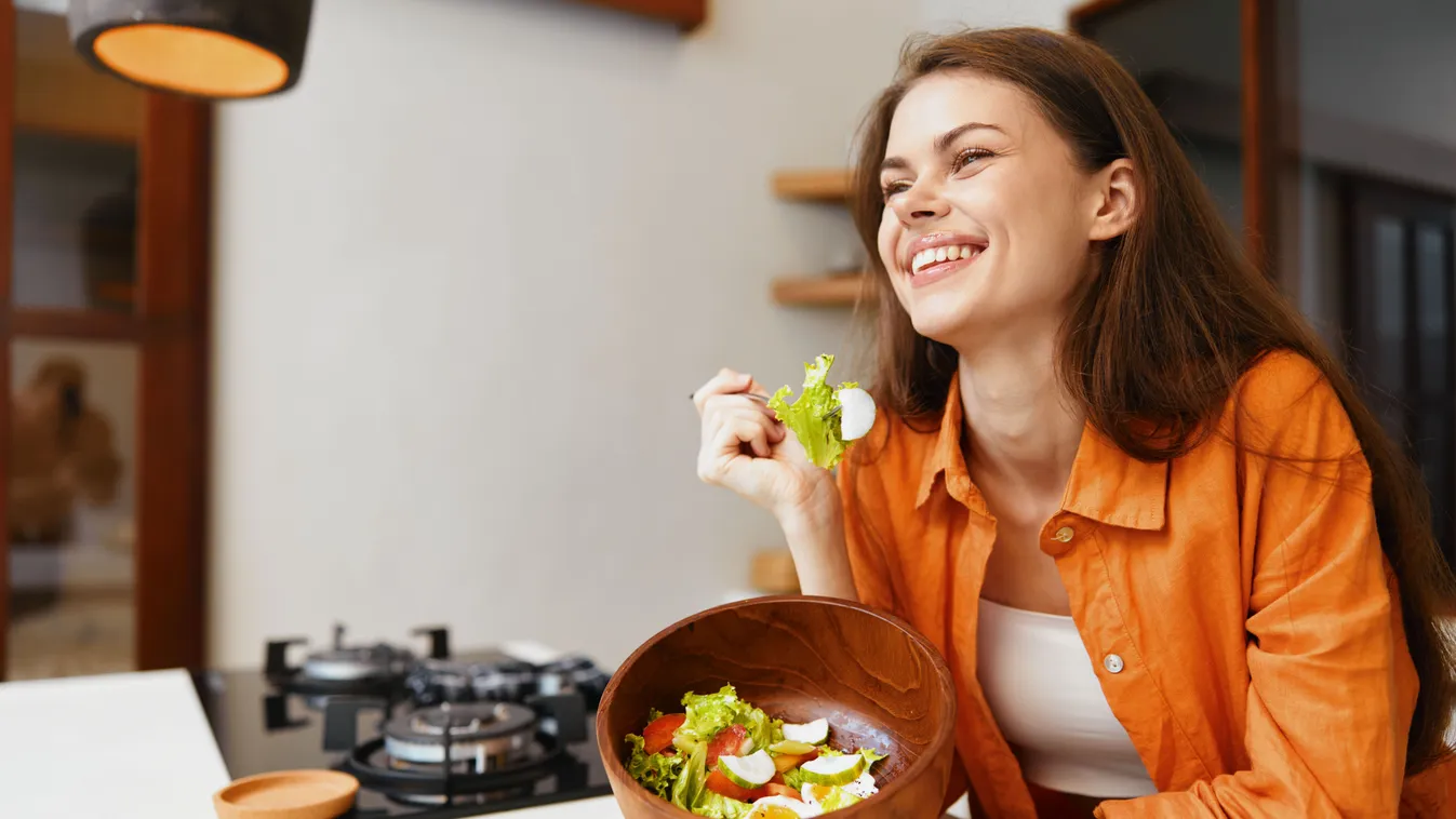 Egészséges táplálkozás részeként boldogan salátát fogyasztó fiatal nő