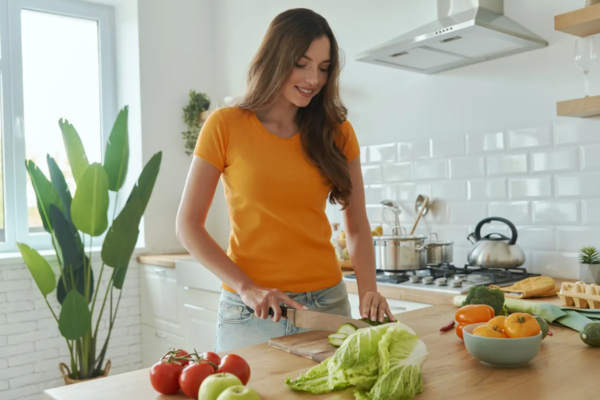 Egészséges táplálkozást követő nő főzés közben a konyhában