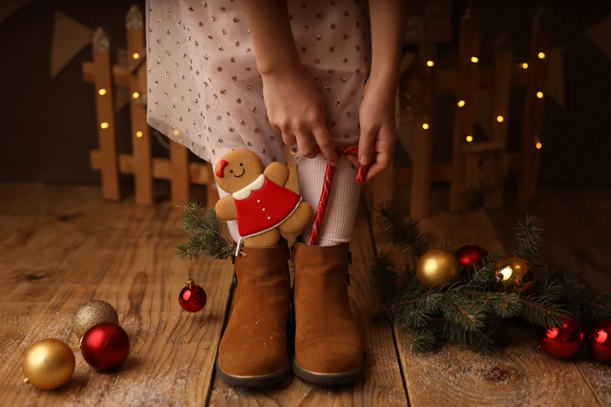 Mikulás csomag gyanánt egy kislány édességet töm a csizmájába.