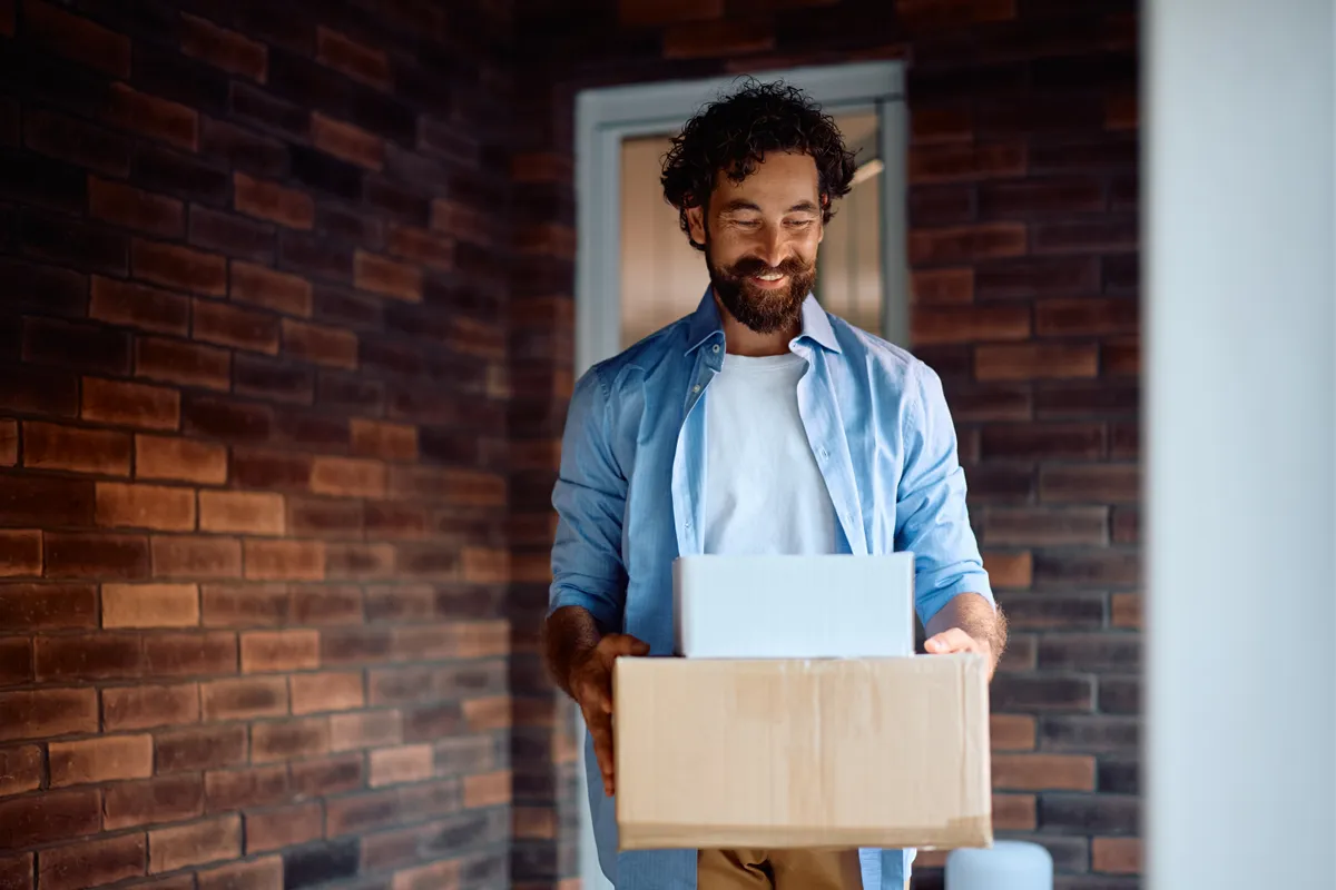 Postai csomagfeladás esetén fordítsunk időt a csomagolásra, akár csak ez a férfi kezében dobozokkal.