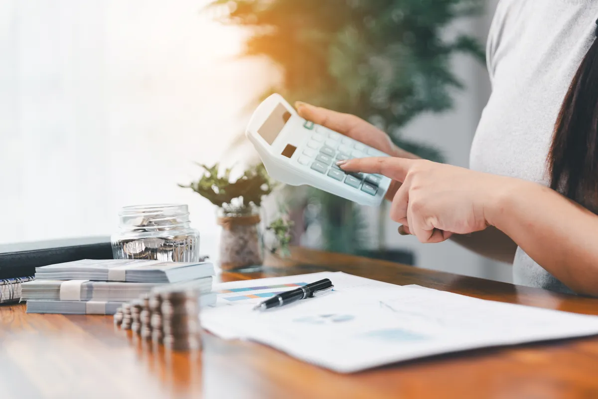 Egy nő számológépen számolja a kiadásait, mert megfogadta a spórolási tippeket. 