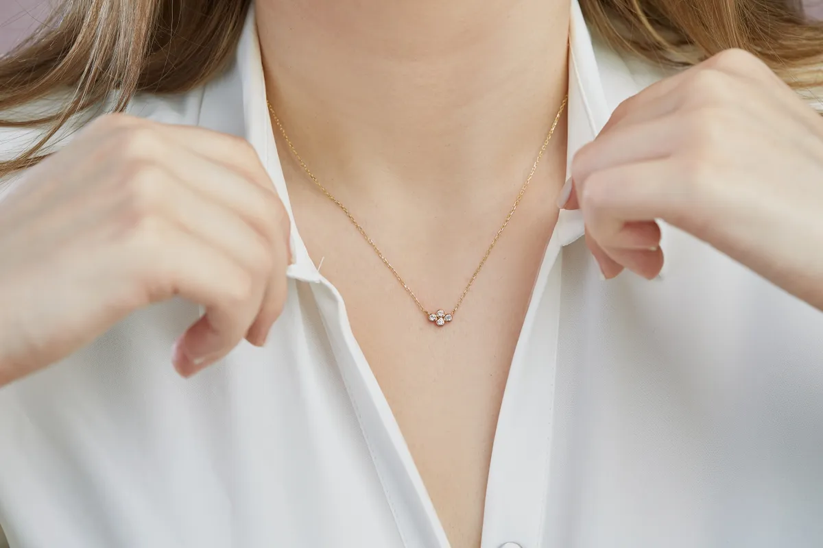 Inget és finom láncot viselő nő, aki az otthoni ékszertisztítási módszerekre esküszik.