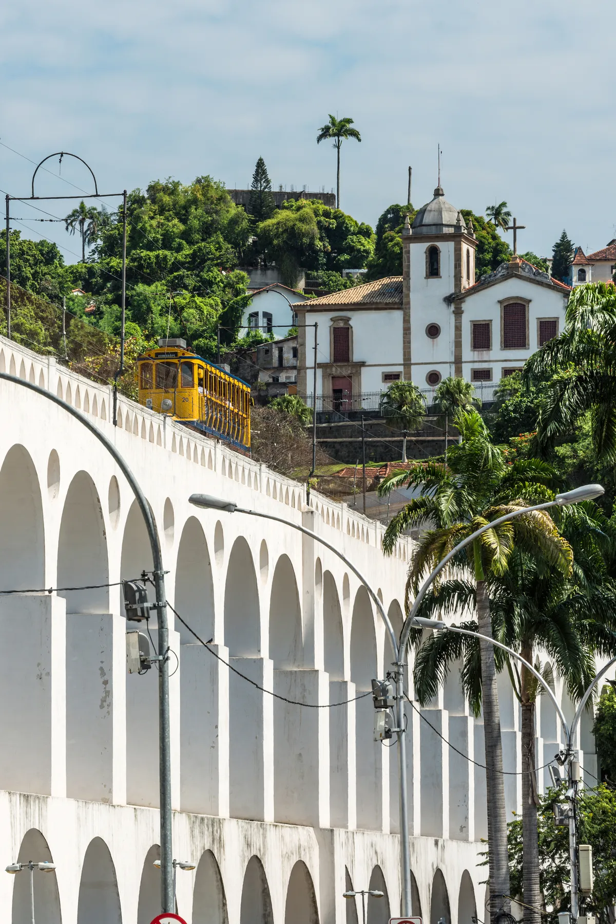 A Rio e Janeiro-i Santa Teresa villamos az Arcos da Lapa vízvezetéken halad át, háttérben egy templom látható.