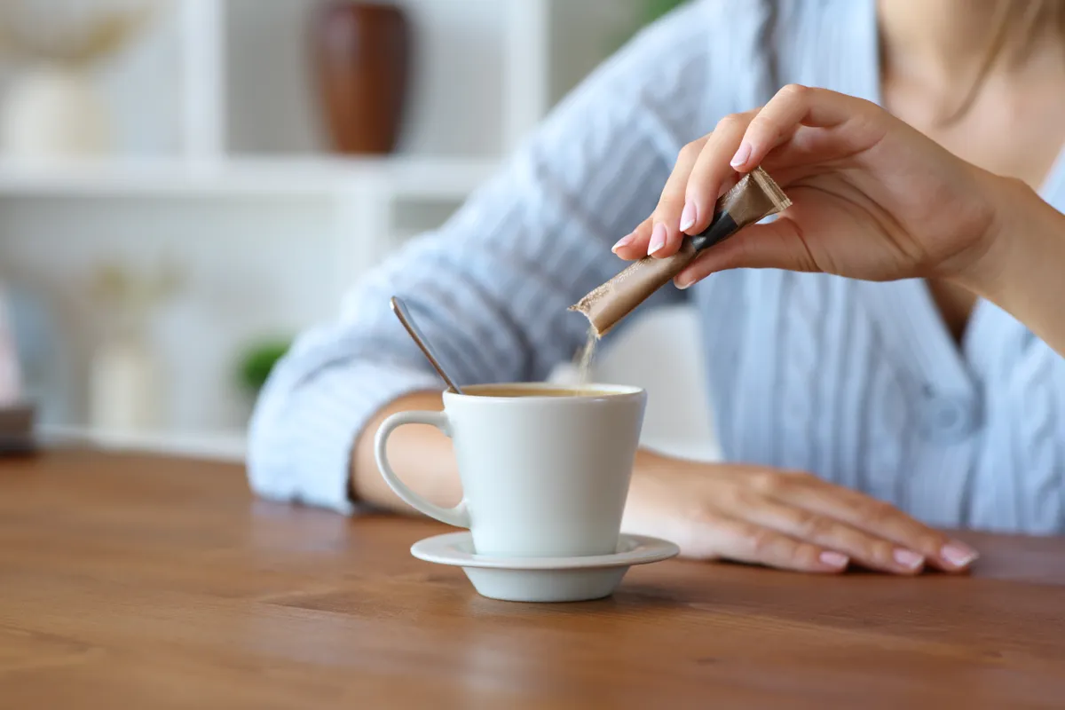 A kávéjába cukrot öntő nő, akinek nem számít a diéta.