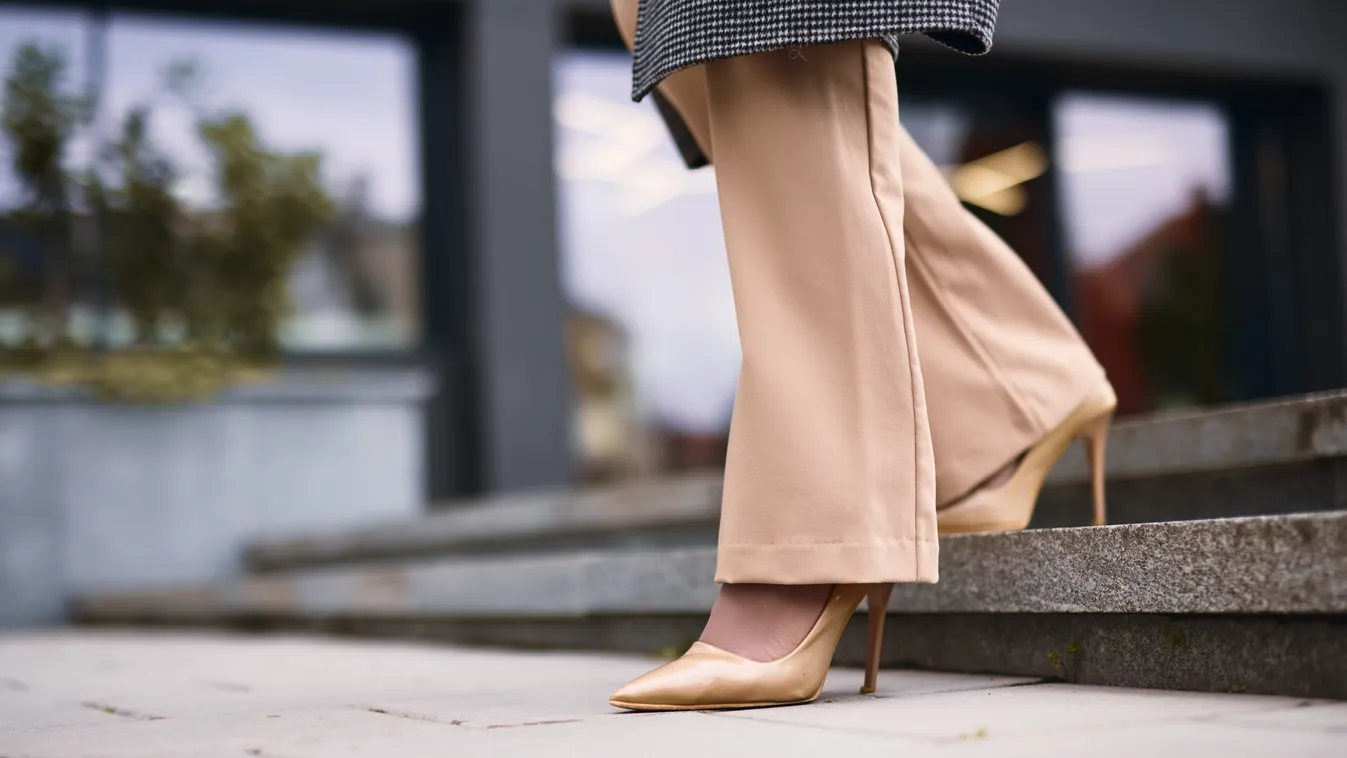 Elegáns szövetnadrágot viselő nő sétál az utcán.