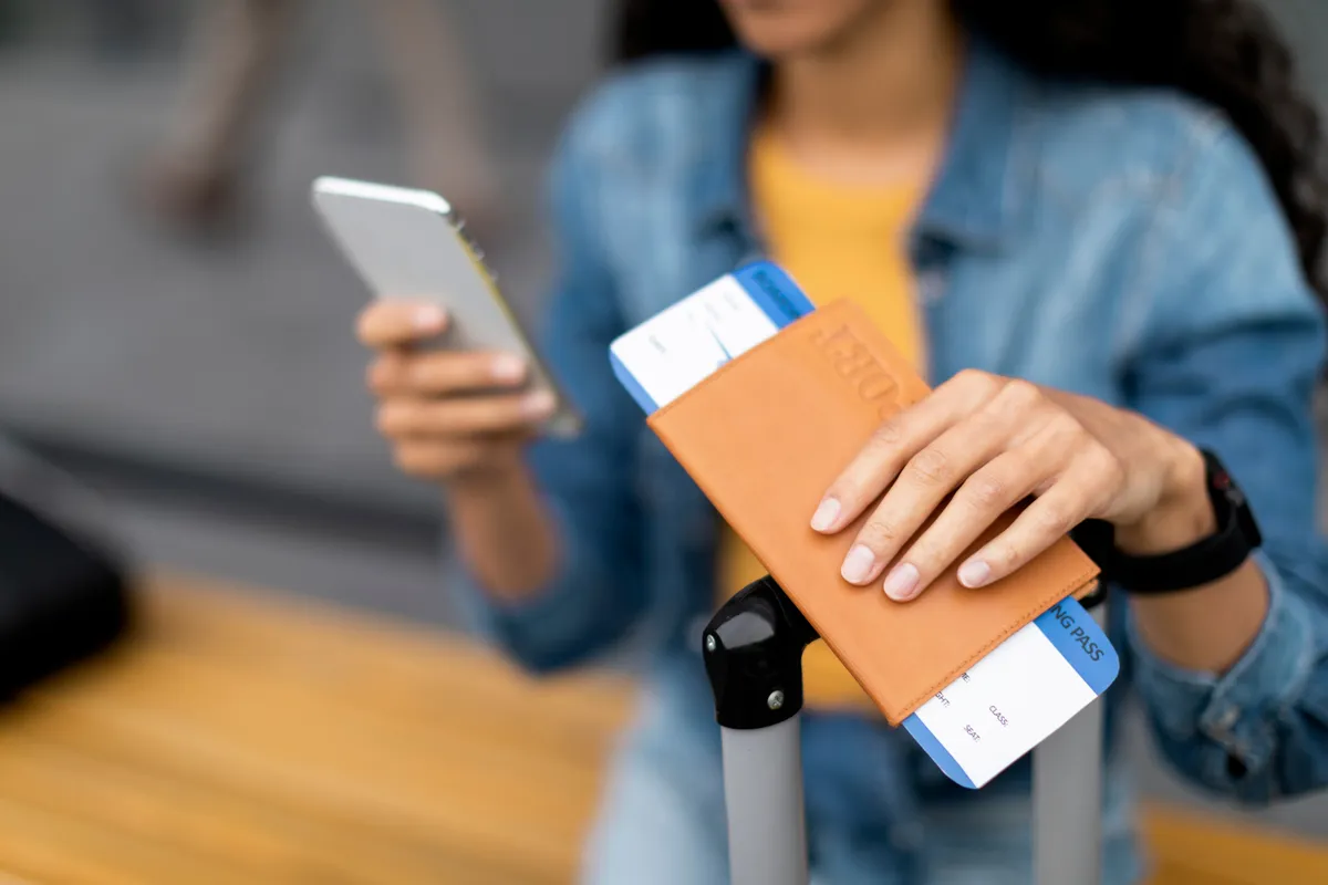 Unrecognizable,Young,Woman,Tourist,Holding,Flight,Tickets,,Passport,And,Modern