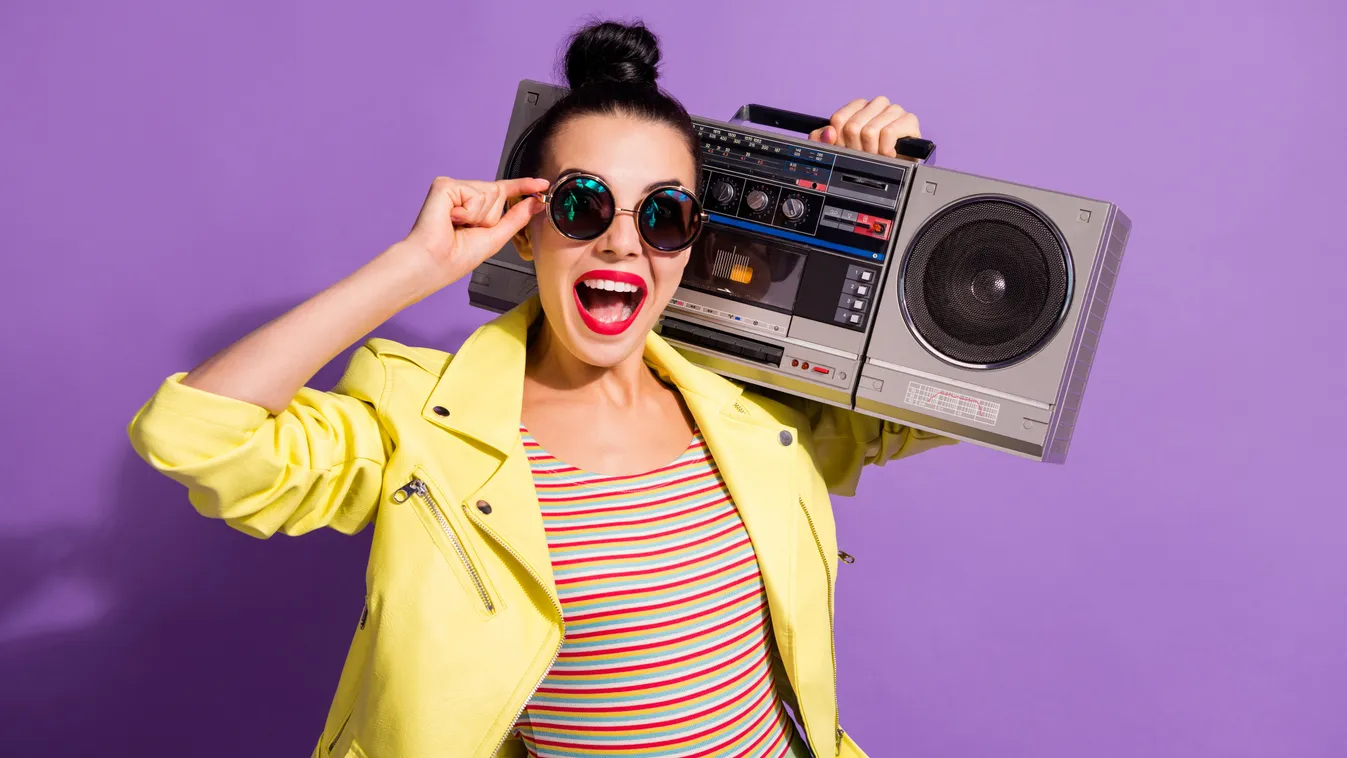 Retró kvízben szereplő régi slágereket nagy magnón hallgató fiatal nő