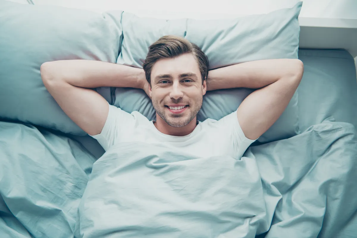 Elégedett, boldog férfi az ágyban fekve együttlét után