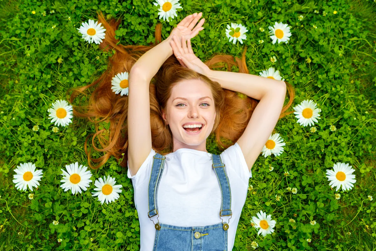 Fiatal lány fekszik a fűben tavaszi virágok között