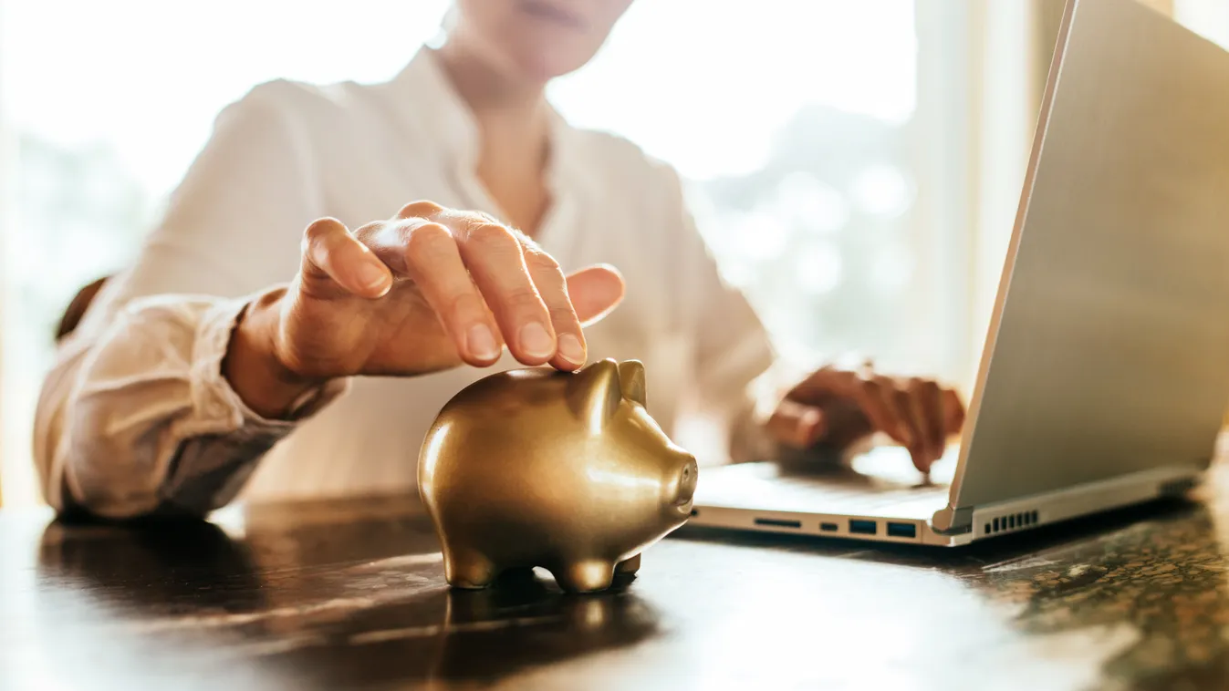 Jó spórolási tippeket követő nő, aki éppen pénzt dob be a perselyébe.