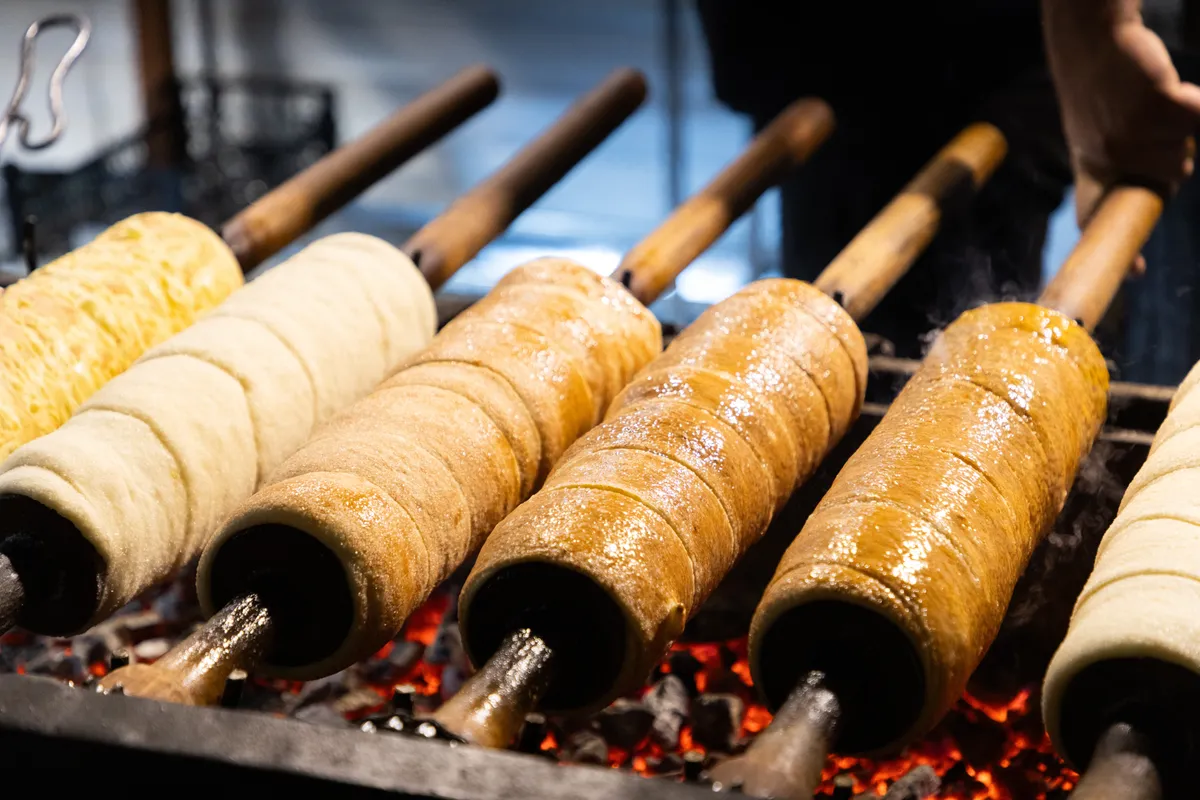 kürtőskalácsokat sütnek rudakon, parázs felet.