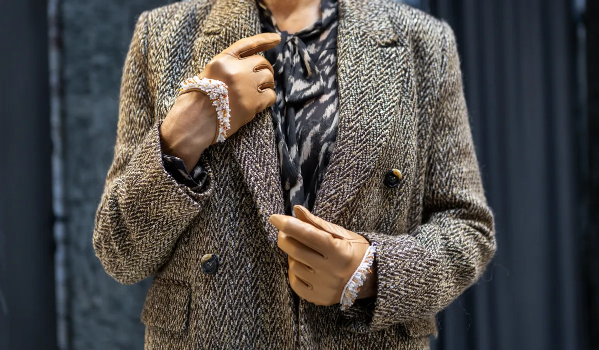 Női divat 50 felett: csillogó blézert viselő nő kesztyűben.