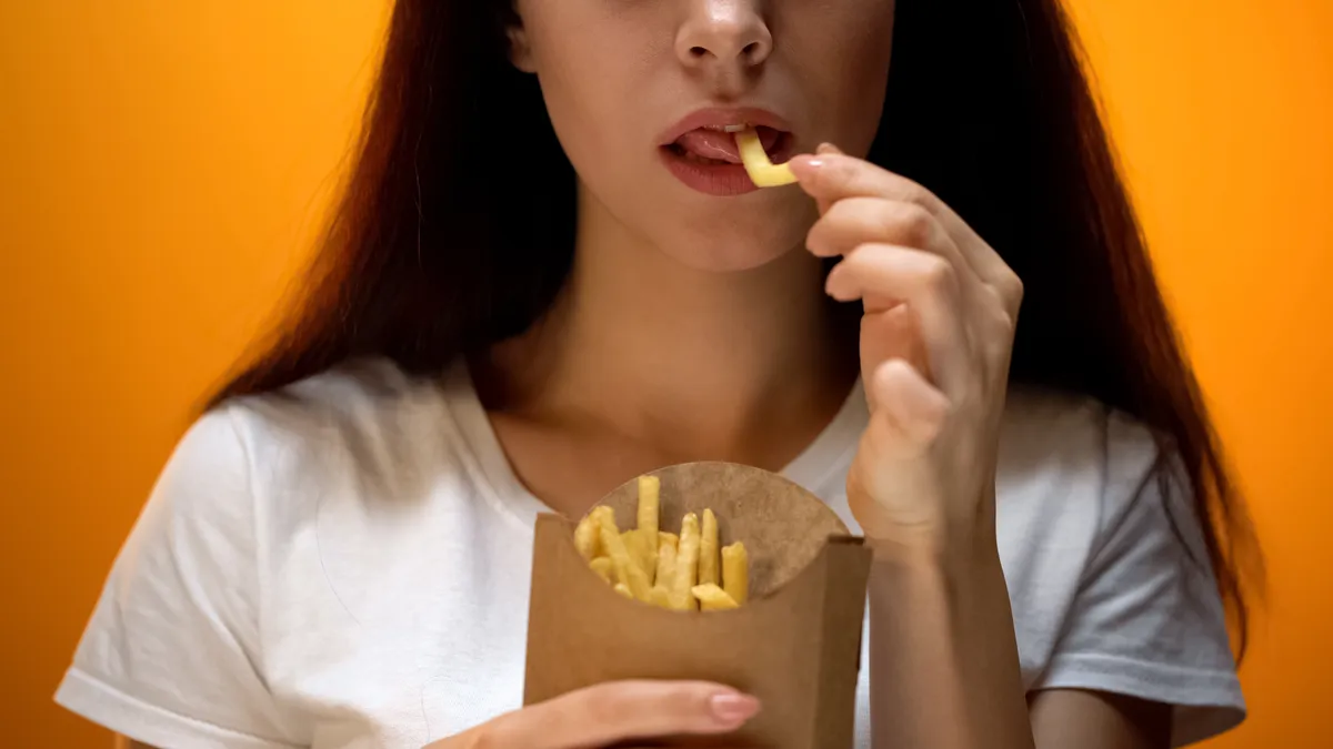 Sült krumplit, a boldogtalanító ételek egyikét fogyasztó fiatal nő