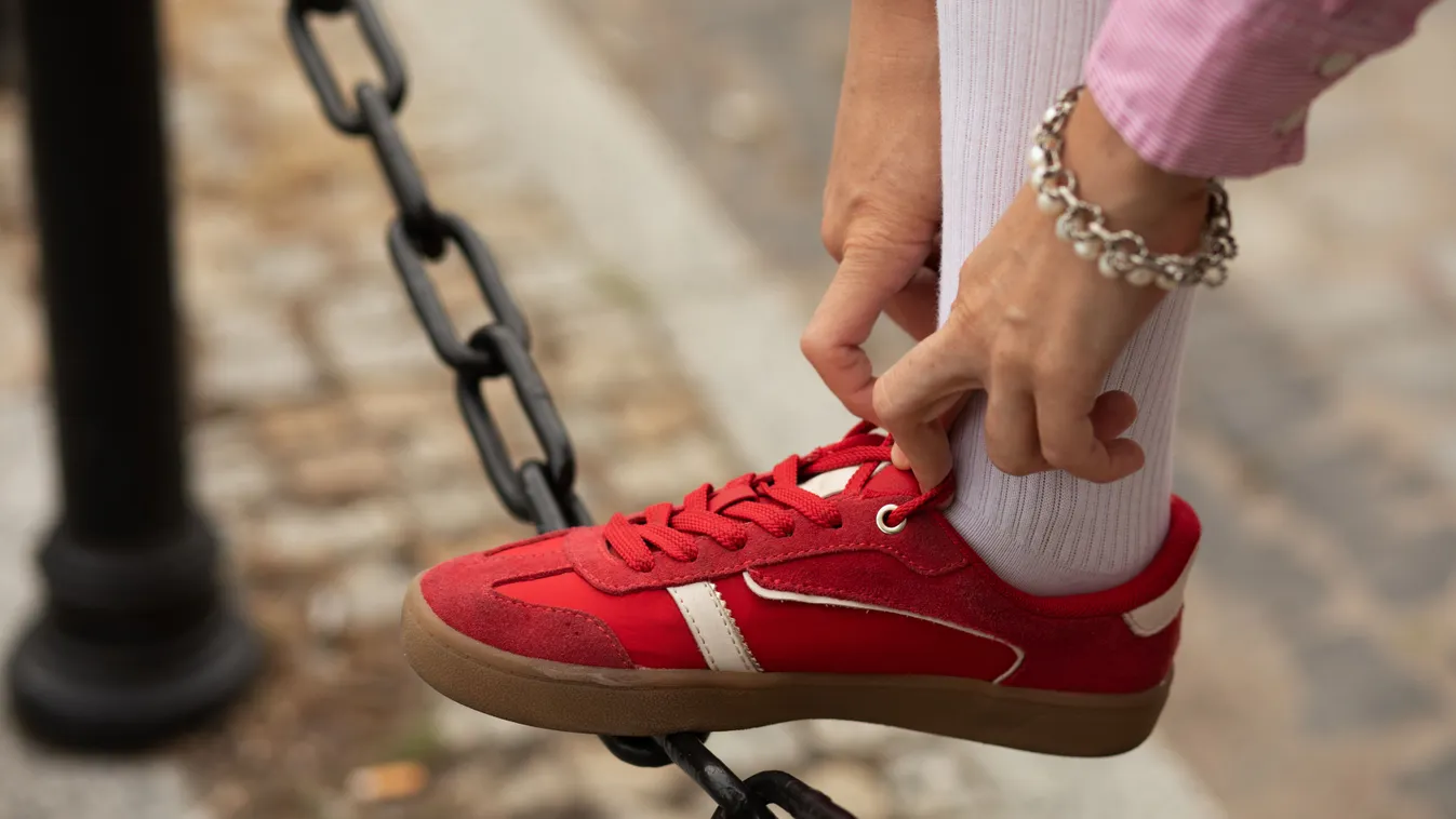 Trendi sportcipőt viselő nő cipőfűzőt köt