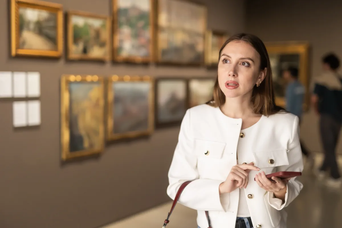 Egy nő a műzeumban épp a művészettörténeti kvízünket tölti ki a telefonján.