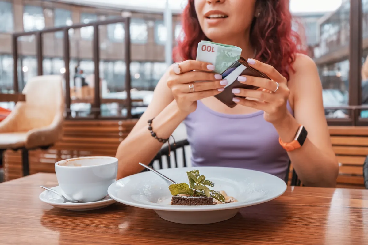 egy fiatal vöröshajú nő fizet és borravalót ad a desszert után.