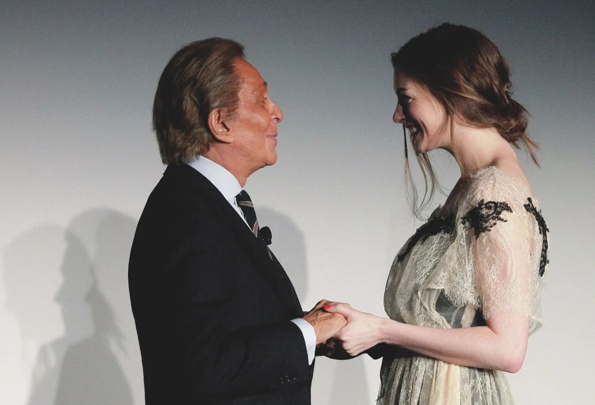Designer Garavani speaks to actress Hathaway after a news conference during the opening of the Valentino Garavani Virtual Museum at the Museum of Modern Art in New York