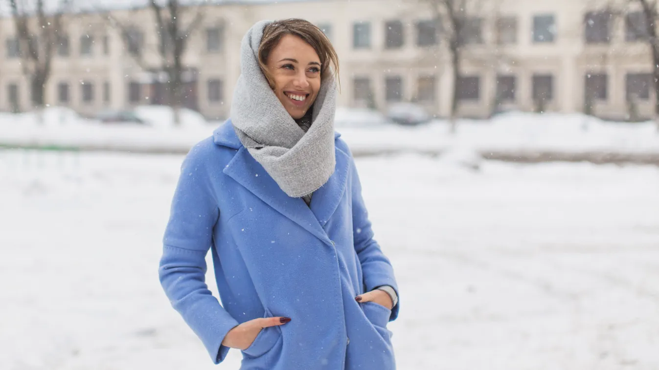 Divatos téli szettet viselő nő kék kabátban.