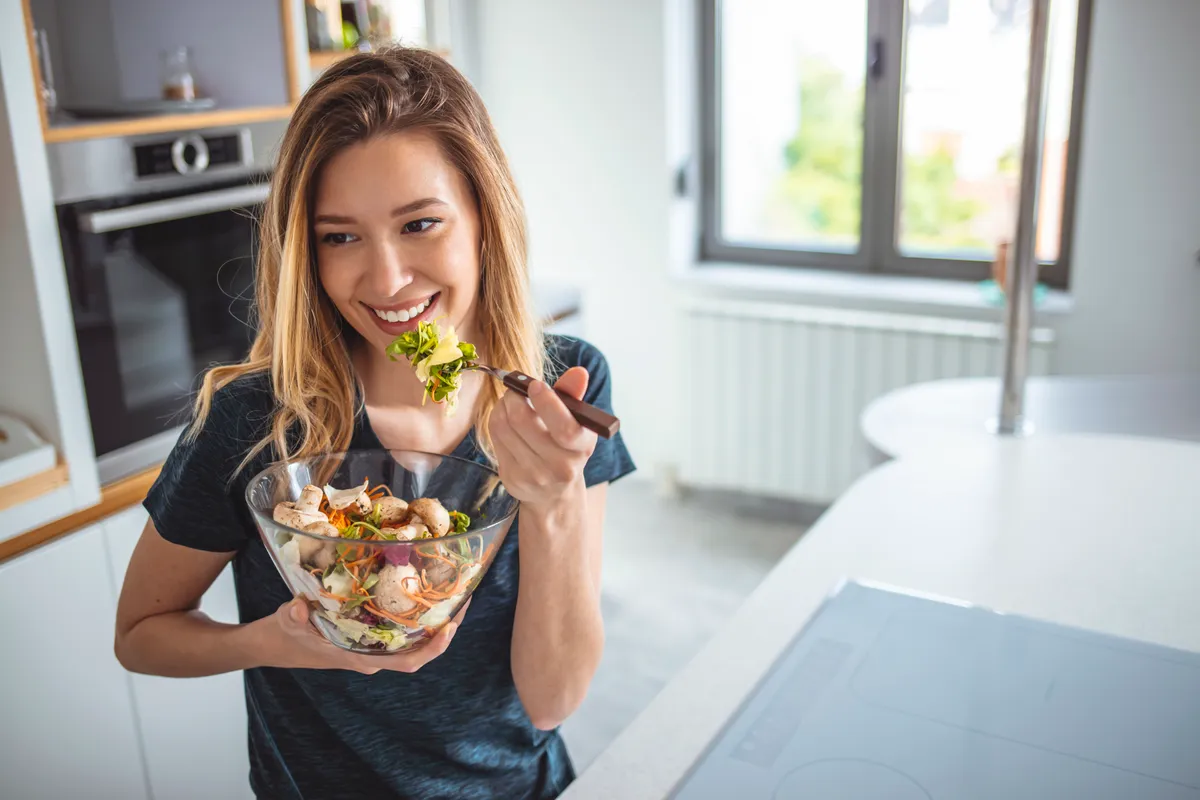 Paleo étrendet követő nő húst és zöldséget eszik.