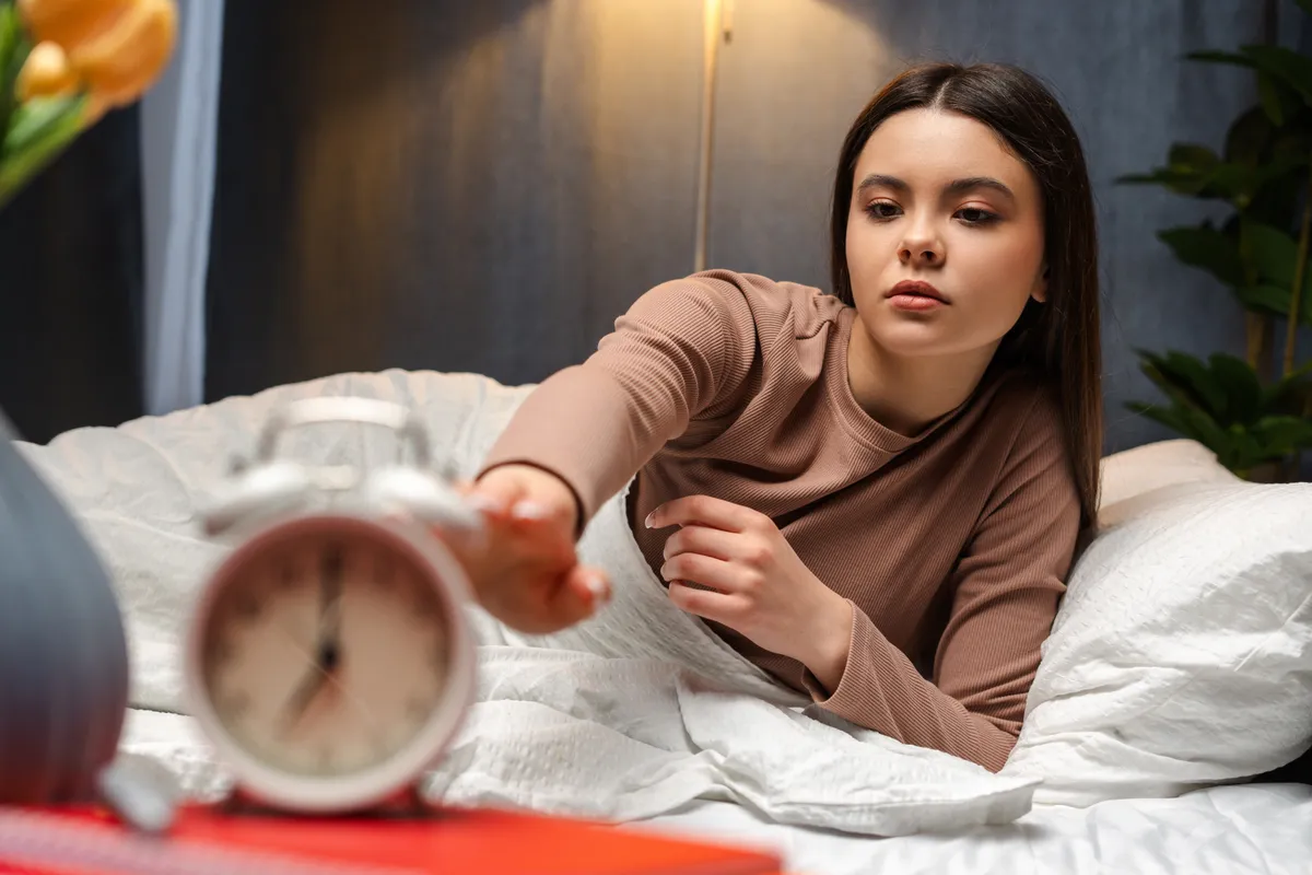 Ébredés után egy fiatal lány lenyomni készül az ébresztőórát.