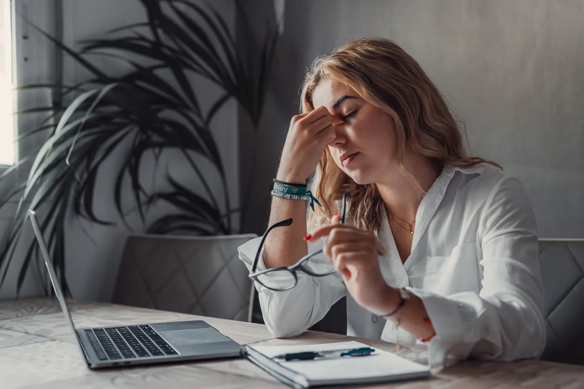 Egy nő a számítógépe előtt ül, fáradt mert C-vitaminhiánytól szenved.