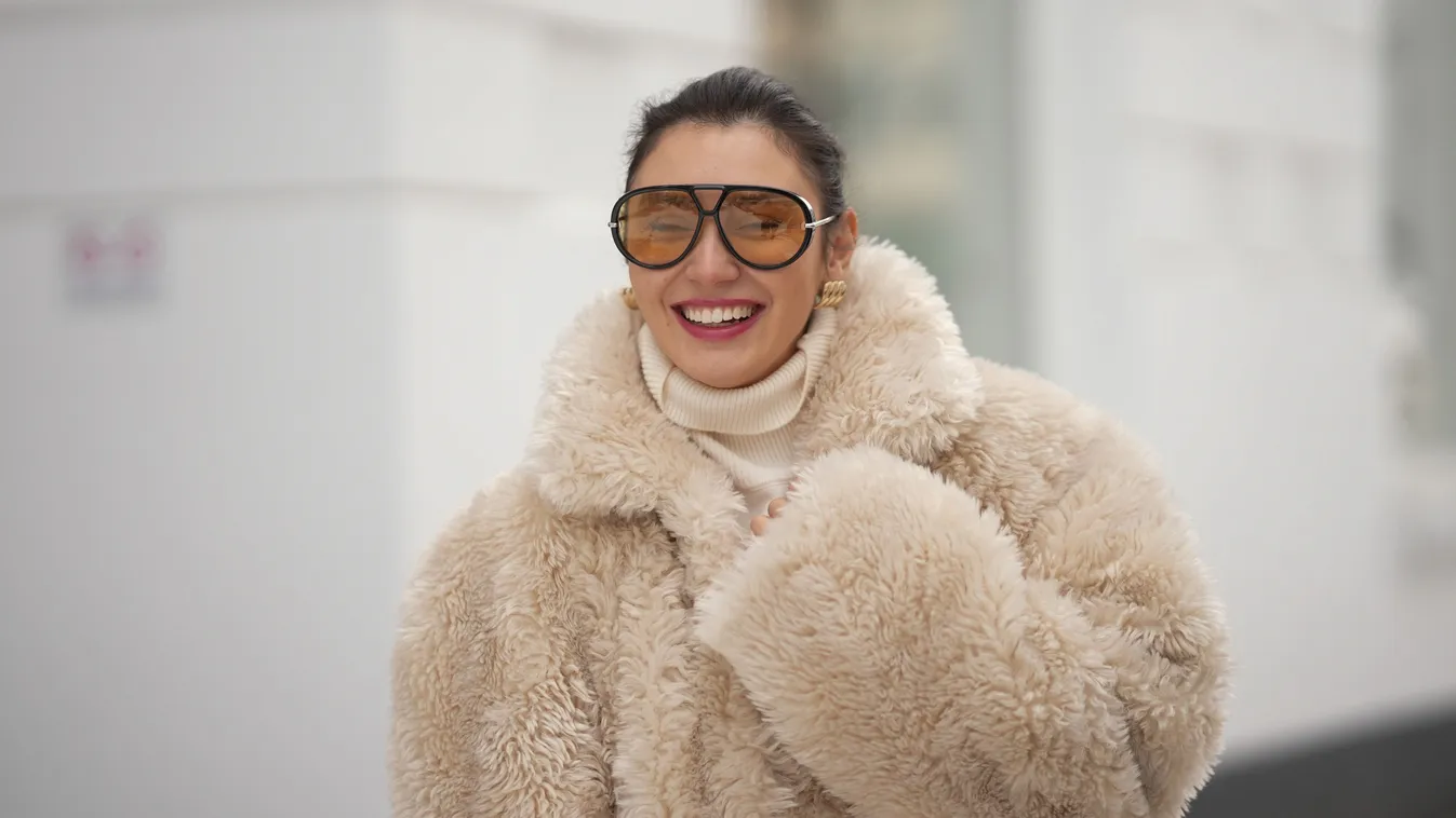 Divatos téli szettet viselő nő, nagy kabátban és napszemüvegben.