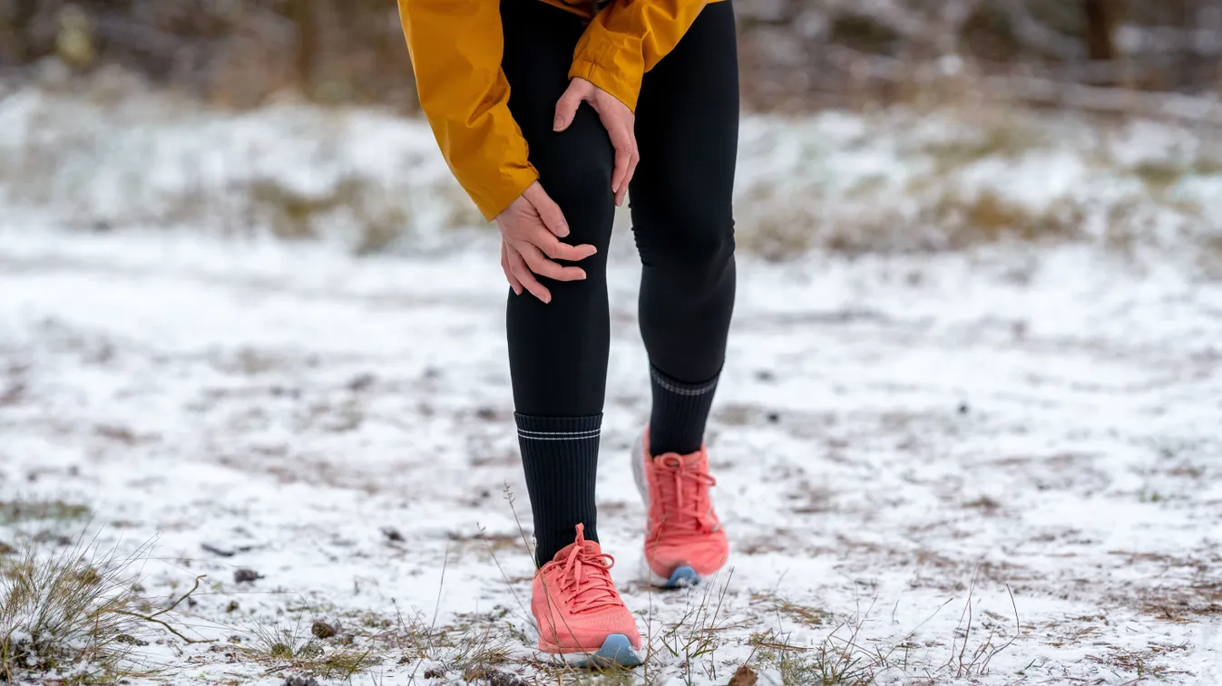 Téli ízületvédelemről nem gondoskodó, térdét fájlaló nő futás közben a szabadban
