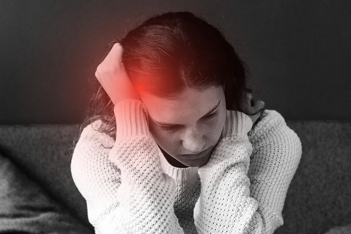 Fejfájást tapasztaló fiatal nő.