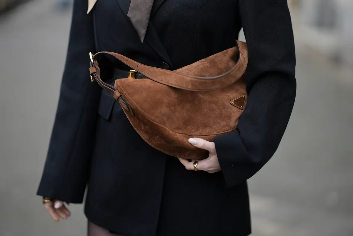 Egy divatos nőnek velúr táska van a kezében.