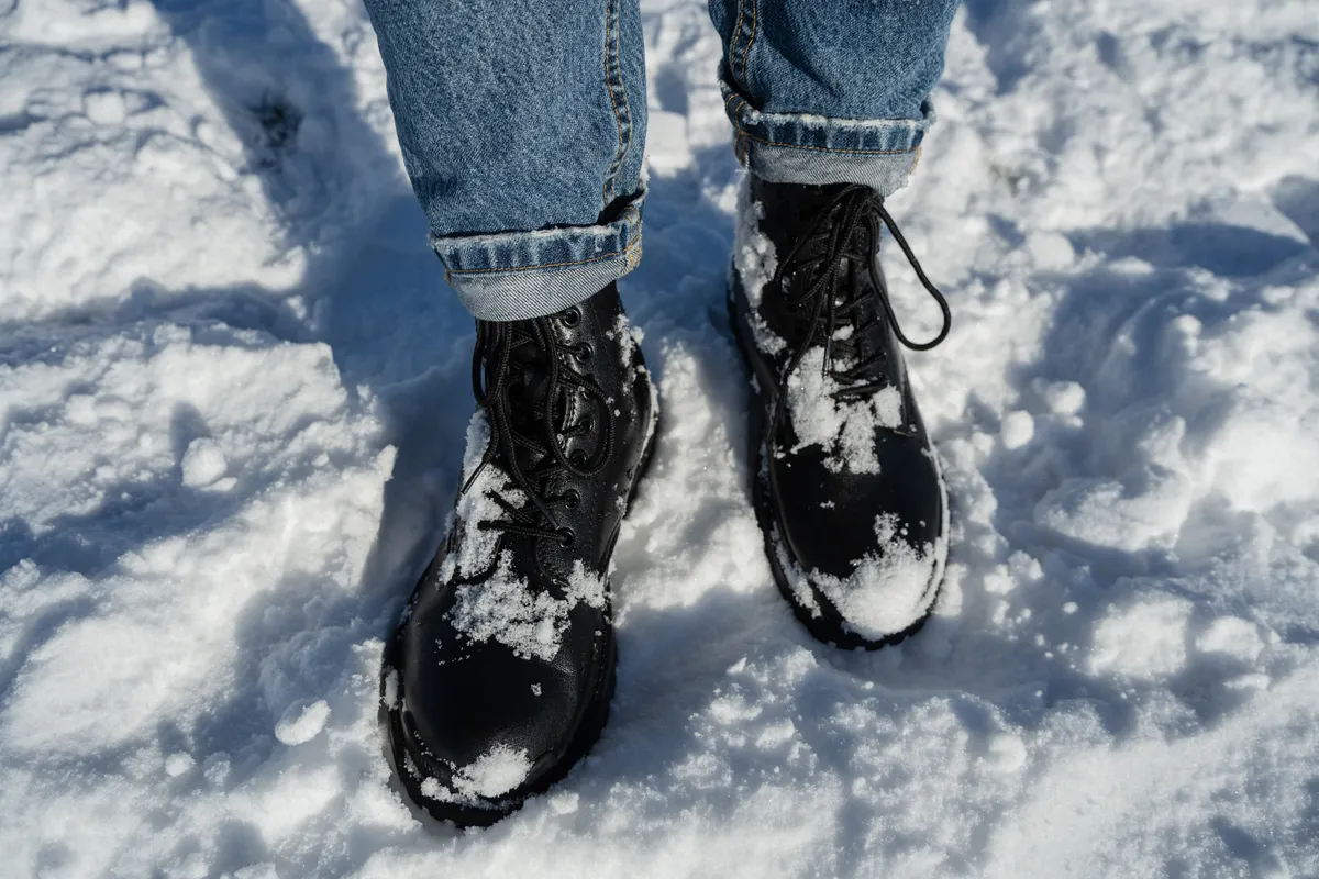Téli bakancsot viselő nő sétál a hóban, aki számára fontos a cipőimpregnálás.