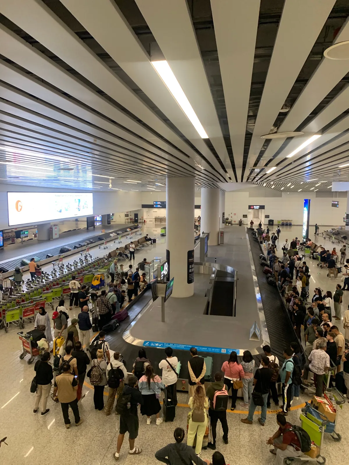 tömeg egy kínai reptéren a csomagkiadó szalagoknál.