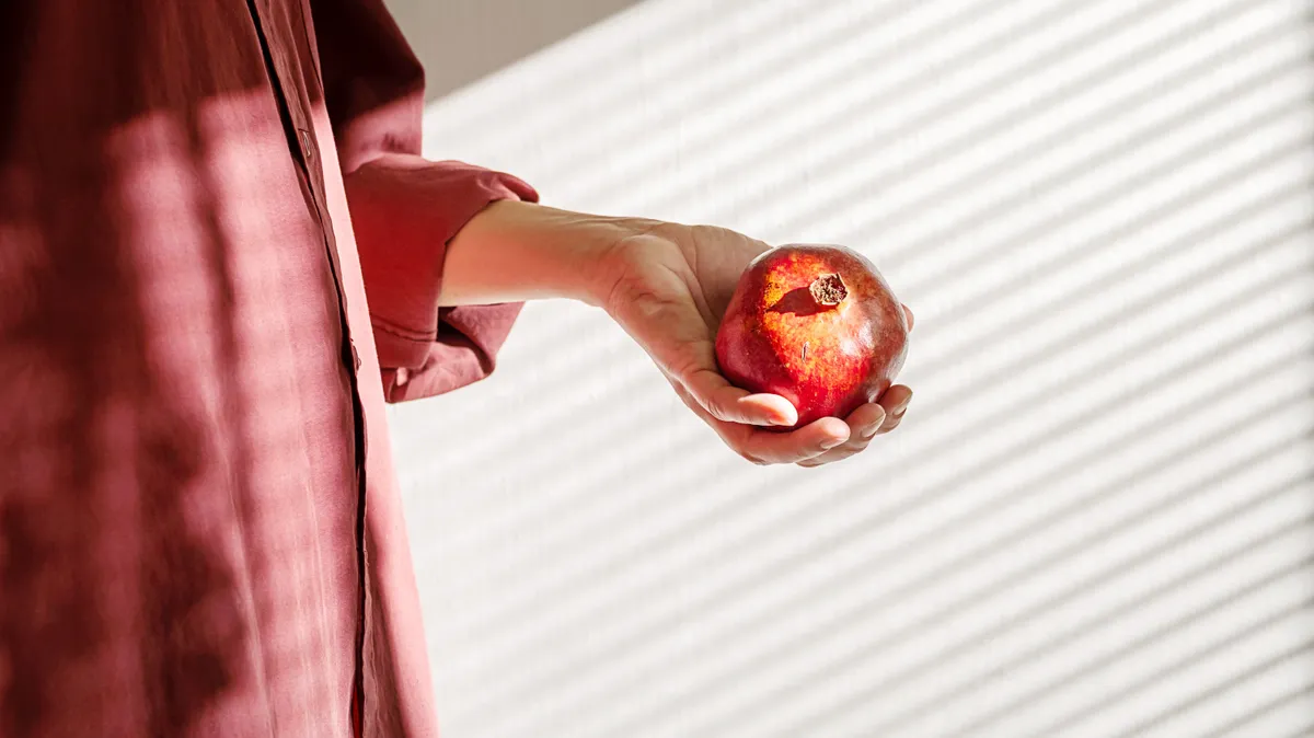 Gránátalmát kezében tartó nő, aki tudja, hogy a gránátalma hatása a szervezetre pozitív